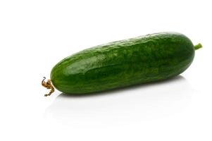 Vibrant cucumber resting on a clean white surface illuminated by soft light in a kitchen setting photo