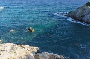 Crystal clear waters gently lapping against rocky shores at daylight in a serene coastal landscape. photo