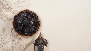 A Lantern and A Plate of Dates With Dry Plants Decoration on Beige Background photo