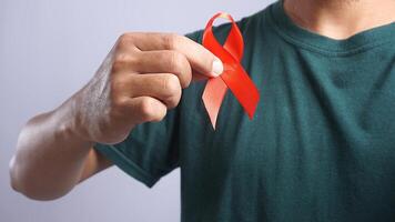 Man Holding Red Ribbon on His Chest Symbolizing Support for People Living With HIV AIDS photo