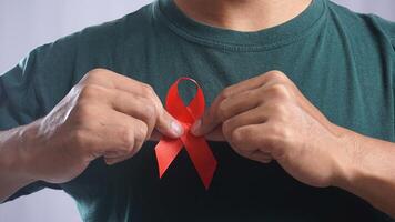 Man Holding HIV AIDS Awareness Red Ribbon in front of His Chest photo