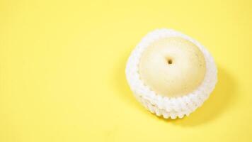Asian or Nashi or Century Pear with White Mesh Foam Wrap Isolated on Yellow Background photo