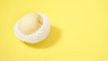 Fresh Asian or Nashi or Century Pear with White Mesh Foam Wrap Isolated on Yellow Background photo