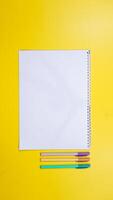 Blank Notebook for Copy Space with Pens Isolated on Yellow Background photo
