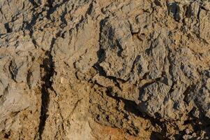 Textures of weathered rock formation illuminated by warm sunlight at the edge of a rugged landscape. photo