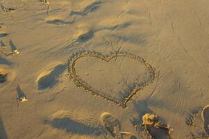A heart drawn in the sandy beach at sunset, capturing a moment of love and tranquility by the ocean. photo