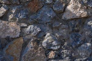 Textured stone wall showcasing a rich mix of colors and shapes under natural light in a rustic setting photo