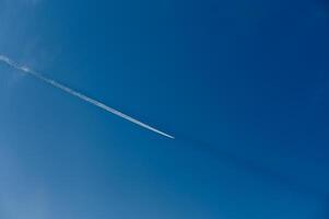 Contrails create delicate patterns across the bright blue sky during a sunny day photo