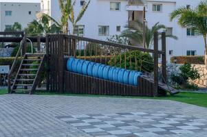 Playground structure featuring bright blue swings in a serene family-friendly park with palm trees photo