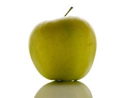 Vibrant green apple standing on a reflective surface under bright light creating a striking visual contrast photo