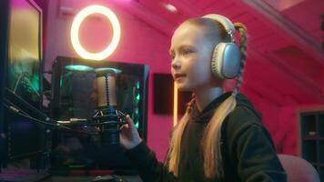 Sad upset little child concentrated worried talk to mic streaming daughter girl kid playing computer game online gaming addicted failure difficult play talking microphone stream neon light gamer video