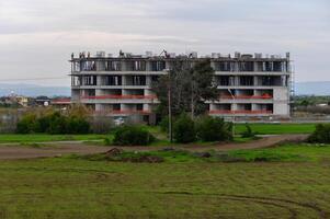 Construction workers diligently build a large modern structure in a rural area under overcast skies photo