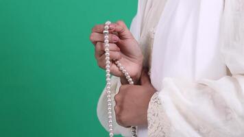 Close-up of two hands holding a string of pearls, wearing a white garment, isolated on a green background or green screen. video