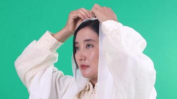 A woman wearing a white veil looks off to the side in profile view, the background is a solid green color. isolated on a green background or green screen video