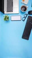 Copy Space with Laptop, Coffee Cup, Smartphone, Glasses, Mouse, and, Keyboard on Blue Background photo