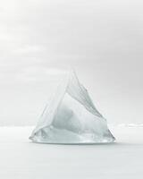 A large ice cube sitting on top of a snowy field photo