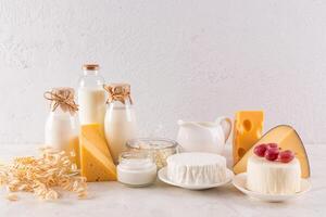 Many different dairy products in bottles and bowls on a stone countertop for the Shavuot holiday. A bunch of ears of wheat, a symbol of the holiday photo
