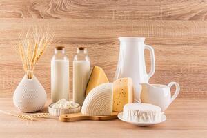 Traditional dairy products in bottles, jugs on a wooden background. a vase with ears of wheat. symbol of holiday Shavuot. Front view. Rustic style. photo