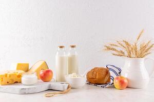 A beautiful still life of traditional products for the Shavuot holiday on a stone countertop in front of a textured wall. A copy space. Front view. photo