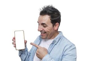 Man smiles while pointing at a blank smartphone screen in a bright setting, showcasing excitement and engagement photo