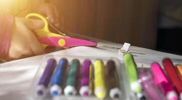 Child's hands using scissors to cut paper. Closeup on kid crafting an art project. photo