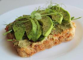 Vegetarian Sandwich Recipe Stock Photo. Yeast Free Toast With Sliced Spicy Avocado Under Peas Grass On White Plate photo