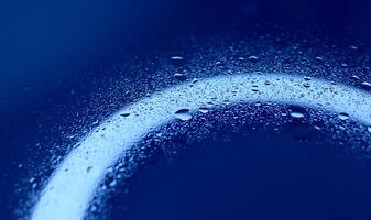 Texture of splashed water on illuminated blue glass surface photo