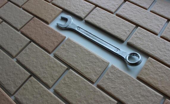 Shiny chrome wrench in place of a missing tile on a fully tiled surface photo