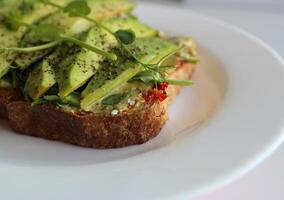 Healthy Nutrition Stock Photo. Detailed Image Of Toasted Bread With Sauce And Topped With Slices of Avocado and Fresh Peas Microgreens photo