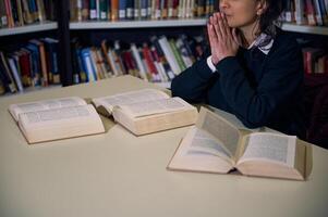 Woman in library studying surrounded by open books on a desk photo