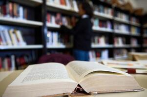 Open book on a table in a library with bookshelves photo