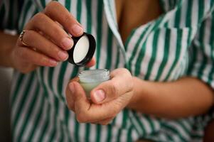 Hands Opening A Small Jar of Skincare Cream in A Relaxed Setting photo