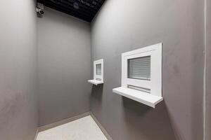 Sanctuary of Surveillance A minimalistic room defined by two white service windows, radiating a sense of security under the watchful eye of a discreet camera. photo