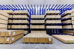 Industrial Harmony A Rustic Collection of Wooden Boards Resting on Vibrant Blue Racks in a Spacious Warehouse photo