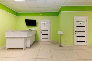Calm Oasis A Green Waiting Area with Doors 3 and 4, Welcoming Visitors with a Small Reception Desk and a Wall-Mounted TV for Relaxation photo