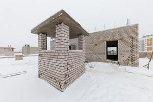Winters Embrace A Frozen Canvas of Unfinished Dreams, Where Snow-Covered Brick Structures Stand in Anticipation. photo