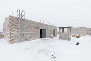 Winters Pause A Brick Building Emerges Amidst the Snowy Silence, Surrounded by Tools and Materials Awaiting the Craftsmans Touch. photo