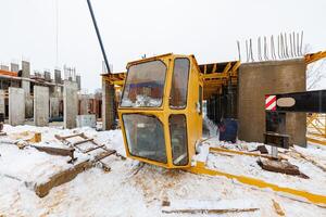 Abandoned Ambition A Snow-Covered Crane Cab Lies Forgotten Amidst Half-Built Concrete Dreams photo