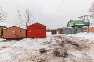 Whispers of Winter A Solitary Row of Garages Enveloped in Snow, Beside a Forgotten Rusted Structure. photo