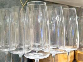 Empty crystal wine glasses neatly arranged in a row on wooden shelf photo