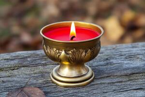 Red candle in an elegant golden candlestick on a wooden surface photo