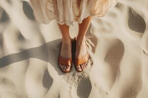 Summer look with a light sand dress and stylish terracotta shoes standing on the sand of the beach photo