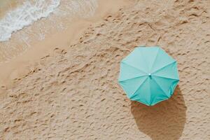 Beach umbrella in turquoise color on brown sand under clear sky photo