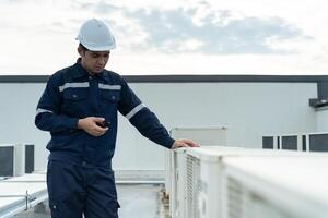 engineer work on the roof of factory. contractor inspect compressor system and plans installation of air condition systems in construction. technology, walky talky, maintenance photo