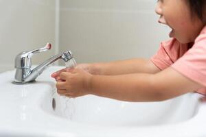 little kid hands wash with soap bubbles and rinse with clean water to prevent and stop the spread of germs after back to home, virus or covid19. Good health and good personal hygiene, virus photo