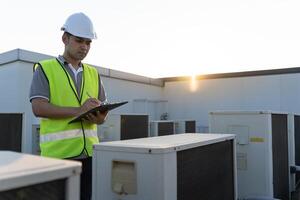 engineer work on the roof of factory. contractor inspect compressor system and plans installation of air condition systems in construction. Checklist, inspector, control photo