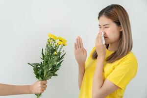 asian young woman sneezing in a handkerchief or blowing in a wipe, allergic to wild spring flowers or blossoms during spring. allergic reaction, respiratory system problems photo