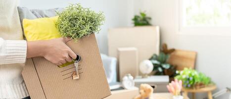 Moving house, relocation. Woman hold carton box contain equipment for new condominium, inside the room was a cardboard box containing personal belongings and furniture. photo