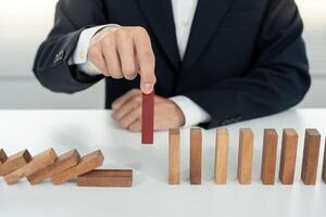 hands protect domino. Businessman hands stop dominoes falling in business crisis. business risk control and planning and strategies to run prevent insurance businesses. photo