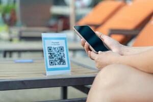 Woman use smartphone to scan QR code for order menu in cafe restaurant with a digital delivery. Choose menu and order accumulate discount. E wallet, technology, pay online, credit. photo
